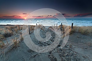 Sand path to beach on North sea at sunset