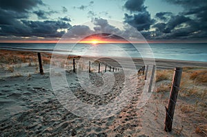 Sand path to North sea beach at sunset