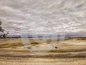 Sand patterns on sandy ocean beach under moody cloudy sky