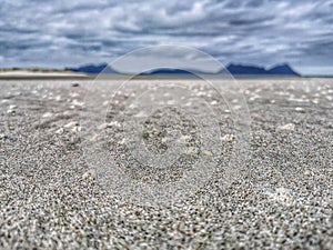 Sand patterns on sandy ocean beach under moody cloudy sky