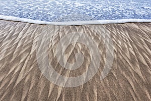 Sand patterns and wave on beach