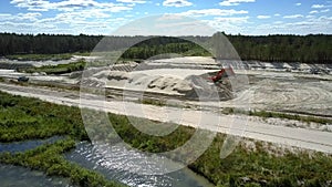 Sand pit with digger at pictorial lake and wood aerial view