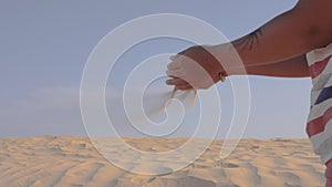 Sand is pouring through the child`s fingers in the wind. Time concept