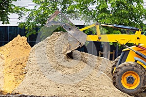 sand pours out of a tractor bucket