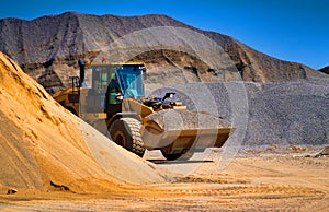 Sand quarry, excavating equipment, bulldozer with heap of sand in background. Selective focus.