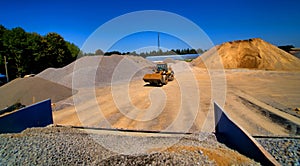 Sand quarry, excavating equipment, bulldozer with heap of sand and gravel in background. Selective focus.