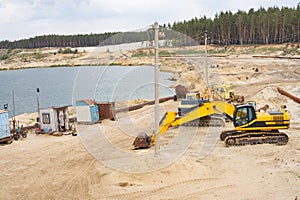 Sand quarry mining industry equipment excavator tractor standing sand land near lake water