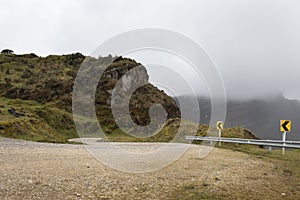 A sand road curve with traffic signals and a high paramo ecosystem peak