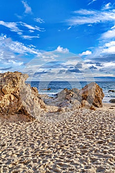 Sand and rocks in Laguna Beach California with sea and cloudy blue sky views