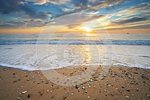 Sand and rocks on seashore at sunset