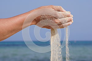 Sand running through hands as a symbol for time running, lost