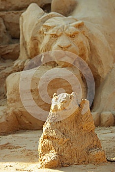 A sand sculpture of a naive waving hamster with a huntin tiger at the backround