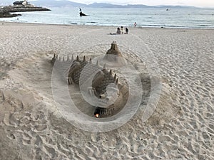 A sand sculpture in the shape of a dragon on the beach