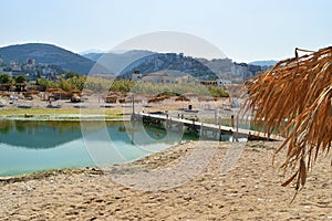 Sand sea and straw umbrella in front of the river Nahr Ibrahim near it`s mouth and the mountains around the valley of the river