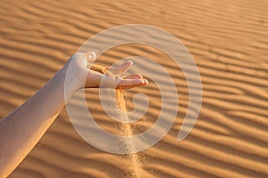 Sand slipping through the fingers of a woman`s hand in the deser
