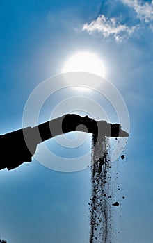 Sand slipping off from hand with sun and blue sky background in Jammu and Kashmir, India