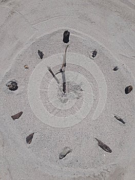 Sand and stick beach clock face 11 o clock
