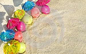 Sand texture (background) with colorful easter eggs with umbrellas on the beach.