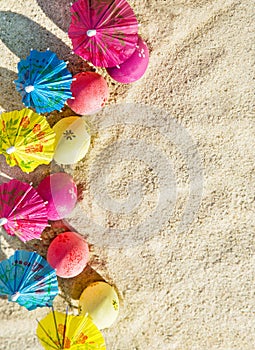 Sand texture (background) with colorful easter eggs with umbrellas on the beach.