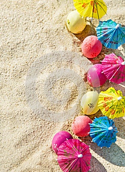 Sand texture (background) with colorful easter eggs with umbrellas on the beach.