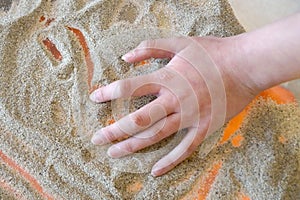 Sand therapy for the development of fine motor skills, children`s hands draw with sand