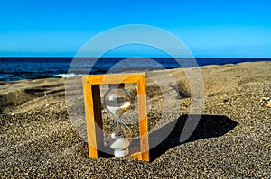 A sand timer is on the beach, with the sand timer showing the time as almost up