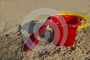 Sand toys, a red bucket and a scoop on the sand,