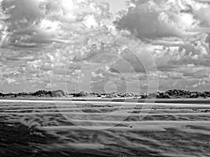 Sand waves in dune landscape by strong sea breeze and dramatic sky black-and-white