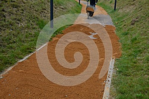 Sand wheeling. garden wheelbarrow carries a worker and pours on piles of beige gravel to repair park, forest, dirt road. erosion c