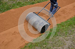 Sand wheeling. garden wheelbarrow carries a worker and pours on piles of beige gravel to repair park, forest, dirt road. erosion c