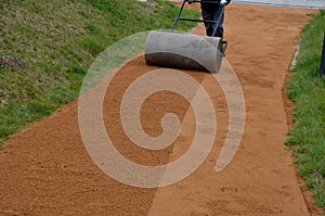 Sand wheeling. garden wheelbarrow carries a worker and pours on piles of beige gravel to repair park, forest, dirt road. erosion c