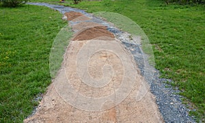 Sand wheeling. garden wheelbarrow carries a worker and pours on piles of beige gravel to repair park, forest, dirt road. erosion c