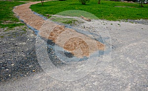 Sand wheeling. garden wheelbarrow carries a worker and pours on piles of beige gravel to repair park, forest, dirt road. erosion c