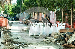 Sand in white plastic nylon bags on the street reconstruction site.