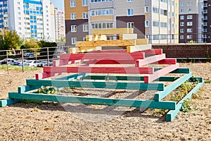 Sand with wooden pyramid with steps which is playground equipment on a public playground in yard in Russia