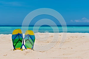 Sandal flipflops on a sandy ocean beach with blue sea and blue b