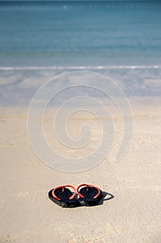 The sandals places on white-yellow sand beach