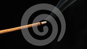 Sandalwood stick with incense smokes on a black background