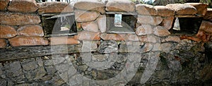 Sandbags piled up in a trench dug in the ground to protect soldiers and slits to look out and shoot from