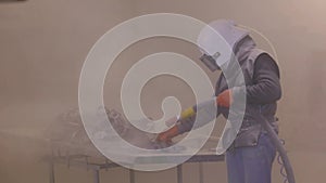 Sandblast metal parts. The man is sandblasting the detail. Sandblasting gun