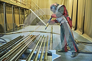 Sandblasting in chamber. Worker makes sand blast cleaning of metal detail