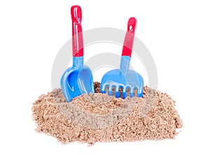 Sandcastle and beach shovels on white