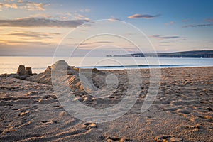 Sandcastle on beach at sunrise