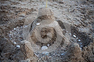 Sandcastle surrounded by rocks on the beach. Building made of sand. Children entertainment making sandcastles. Relaxing time. Kids