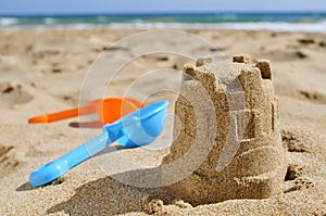 Sandcastle and toy shovels on the sand of a beach