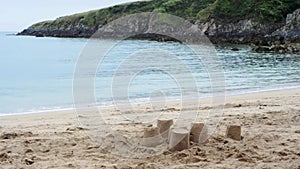 Sandcastles on the beach, gentle waves lapping in a rugged rocky cove