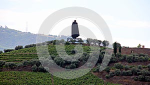 Sandeman silhouette on a hill over vineyards sloping toward Douro River, Peso da Regua, Portugal