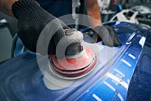 Sander grinding painted bumper in car workshop