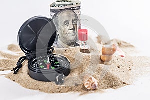 sandglass, dollar and compass on sand isolated on white.