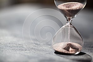 A sandglass, modern hourglass or egg timer with shadow showing the last second or last minute or time out.